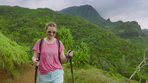 Woman Travels Through a Summer Rainforest with a Backpack and Sticks Hawaii USA alt
