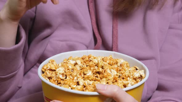 Close Up View on Female Hand Holding and Eating a Popcorn While Watching a Movie in the Living Room alt