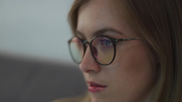 Close up of woman wearing blue light blocking glasses watching TV alt