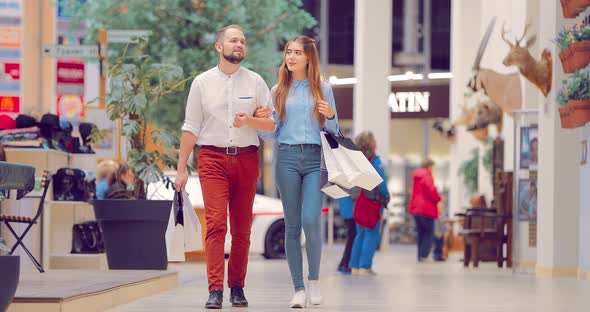 Young Beautiful Couple in the Mall Stops Near the Shop Window alt