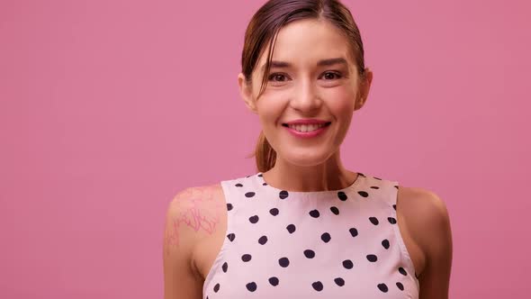 Pleasant Shocked Young Girl Looking at the Camera on a Pink Background. alt