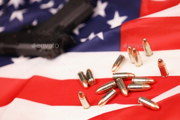 Many yellow 9mm bullets and gun on United States flag. Concept of gun trafficking on USA territory