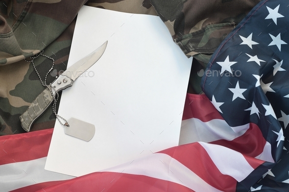 Blank paper lies with knife and army dog tag necklace on camoufl