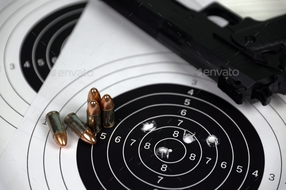 Gun and many bullets shooting targets on white table in shooting range polygon. Training for aiming