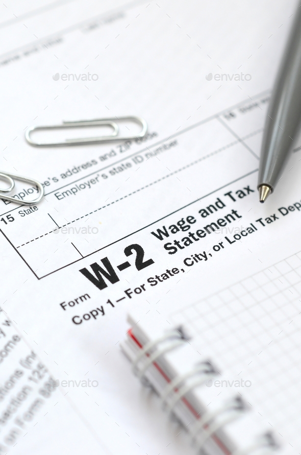 The pen and notebook on the tax form W-2 Wage and Tax Statement. The time to pay taxes