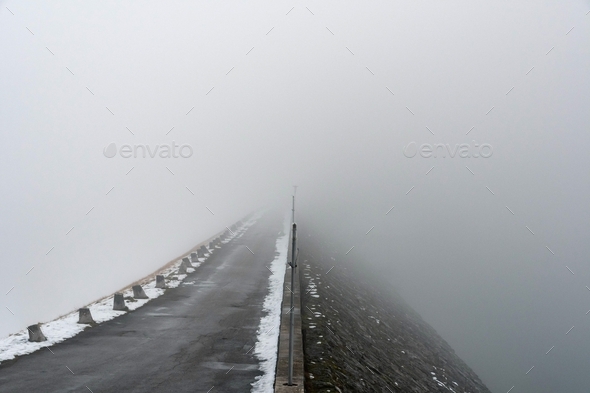 Empty road over a dam. Fog, foggy, way, forward, moody, gloomy, grey.