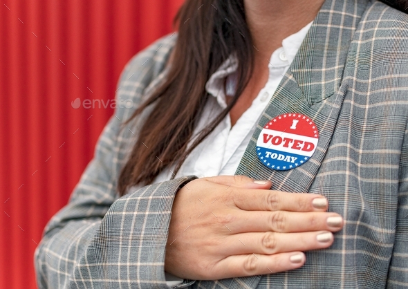 I voted today sticker on woman\'s jacket Woman holding right arm on chest.