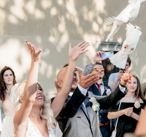 Bride and groom releasing white doves at wedding ceremony in front of church