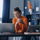 Beautiful woman holding coffee cup and using laptop while sitting at her working place in office - PhotoDune Item for Sale
