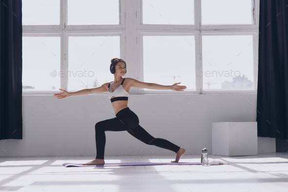 Fit young woman doing stretching exercises while practicing in front of the window - Stock Photo - Images