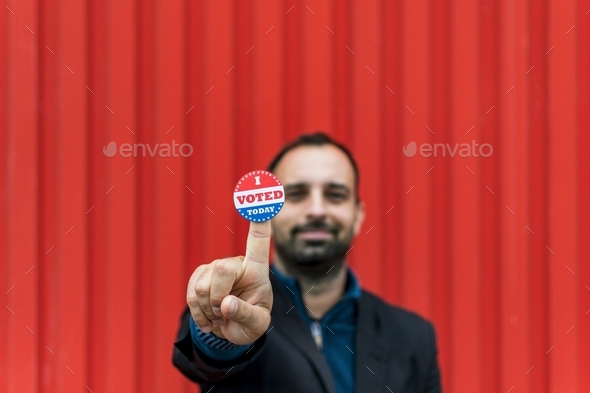 Selective focus image of man smiling and holding voting sticker with i voted today text.