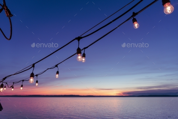 Hanging deck lights at sunset by the sea.  - Stock Photo - Images