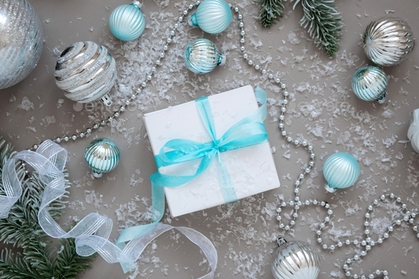 Christmas present in white box blue ribbon grey background with decor and snow