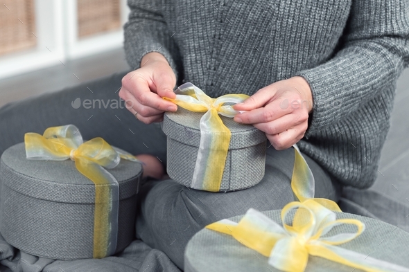 woman pack gifts, grey round box yellow ribbon