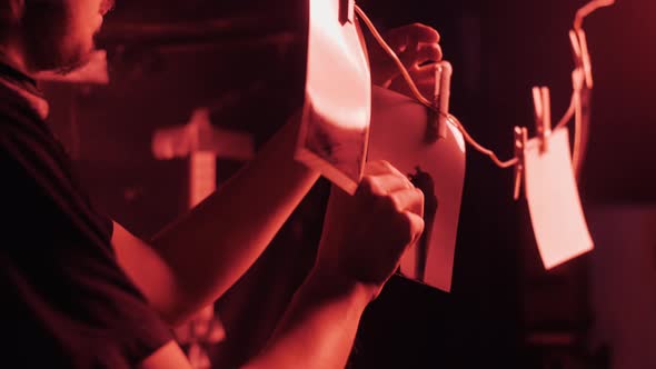 Photographer In Darkroom Hangs Photos alt