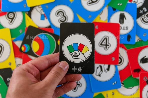 Personal perspective of hand holding black uno card with draw four sign - Stock Photo - Images