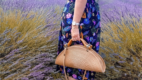 Woman standing in a lavender field. Woman holding a basket bag. Lower section.