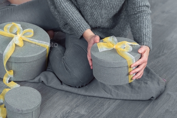 woman pack gifts, grey round box yellow ribbon