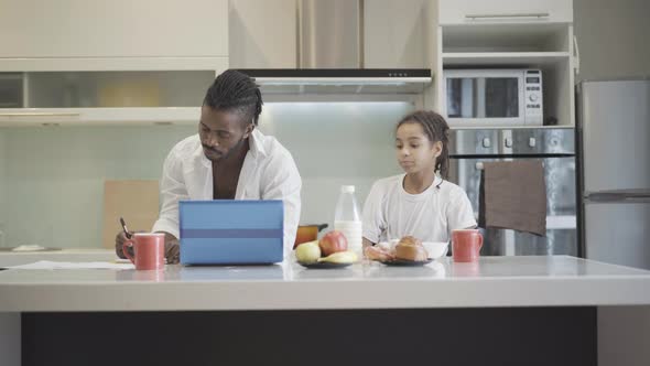 Wide Shot Positive African American Man Working Online As Daughter Having Breakfast Kitchen alt