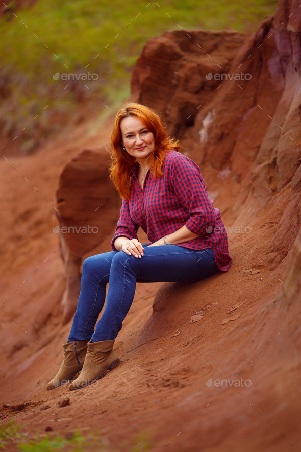 red-haired beautiful woman on a background of gray rocks of the canyon