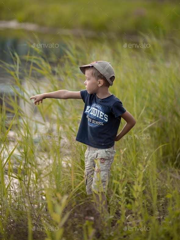 boy 6-7 years old fishing with a fishing rod on the lake Stock