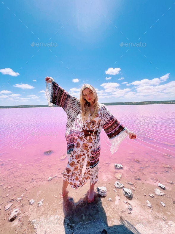 Beautiful young traveler girl wearing boho outfit exploring Hot Lagoob pink lake in Australia