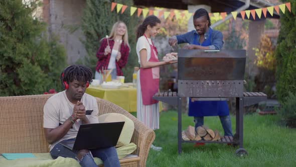 Portrait of Busy Young Man in Headphones Conferencing Online on Laptop Cheerful Group of Friends alt