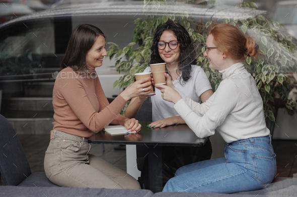 three female friends are talking in a coffee shop and drinking tea, moral support and caring