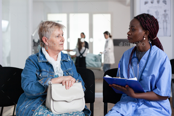 African american nurse filling out elderly woman admission paperwork - Stock Photo - Images