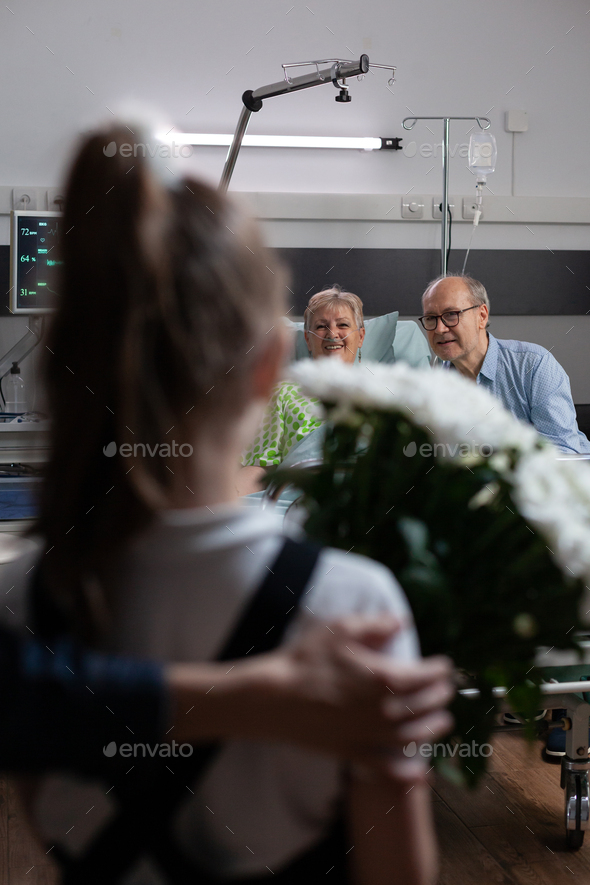 Elderly couple happily greeting relatives in geriatric clinic room - Stock Photo - Images