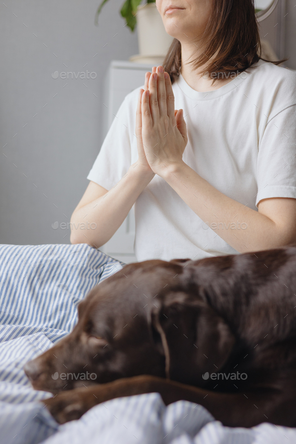woman meditates after sleeping in bed with her Labrador retriever dog. the mental state and mental
