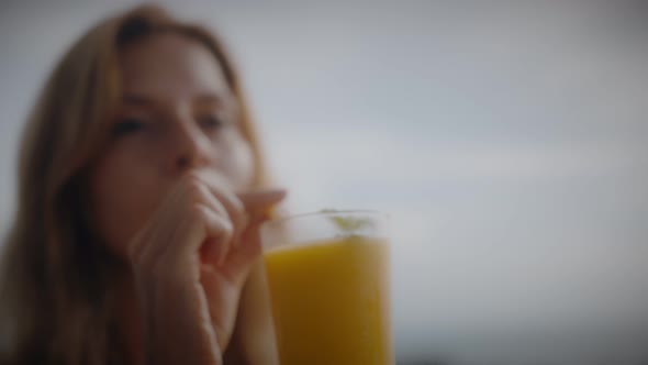 A Blonde Woman Drinks Mango Shake While Lounging in the Sun By the Pool on Vacation alt