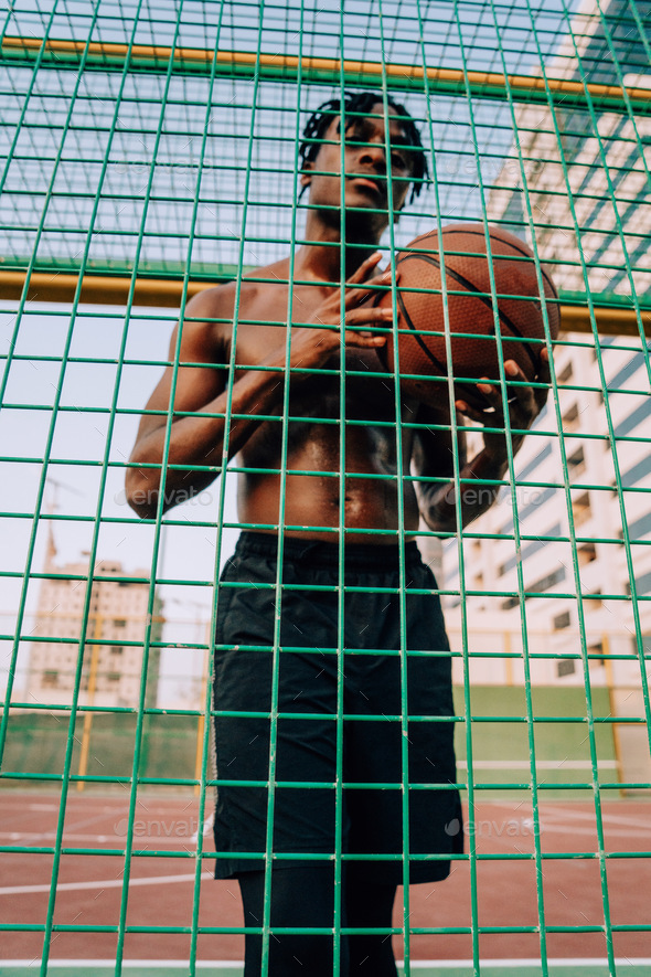 Black man with the basketball behind the fence