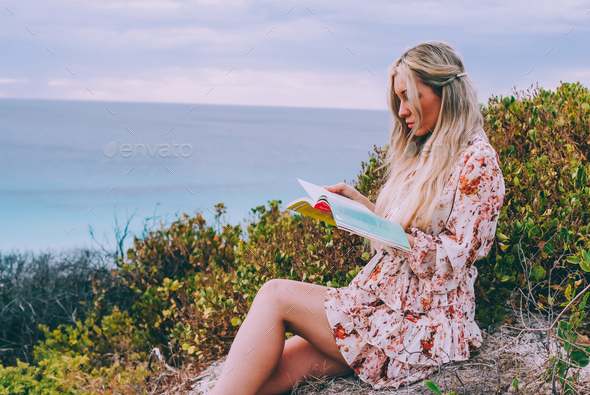 Woman with long hair reading a book outdoors  - Stock Photo - Images