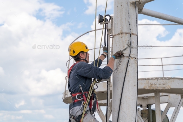 A worker with climbing equipment serves a city TV tower. Work at a high-rise facility.