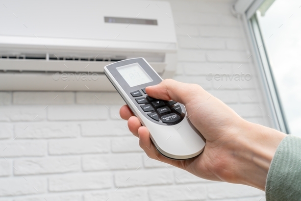 home air conditioner and man hand with remote control closeup - Stock Photo - Images
