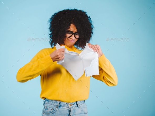 Breaking contract. Furious young african american woman with afro hairstyle tearing up paper on blue