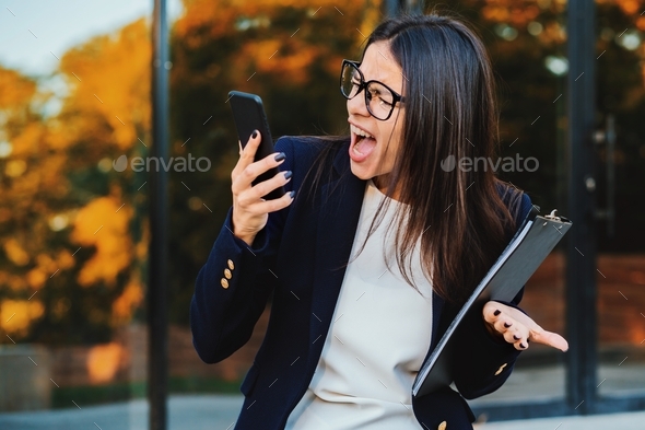 Businesswoman screaming on mobile phone. Having nervous breakdown at work, screaming in anger