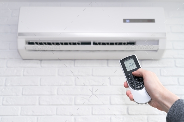 home air conditioner and hand with remote control  - Stock Photo - Images