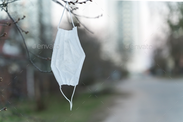 Cancel mask mode - used disposable mask hanging on a tree branch, copy space