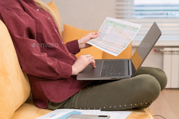 girl of European appearance on the couch with a laptop and business documents