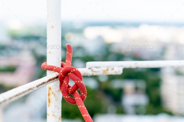 The safety rope is tied with a strong knot. Work at a high-rise facility.
