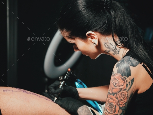 Artist prepares tools and machine for tattoo session, woman holding a tattoo gun