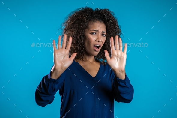 Angry annoyed woman raising hands up to say no stop