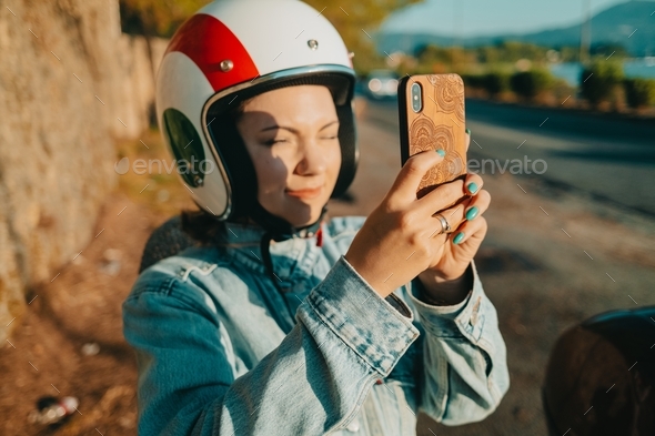 Woman in motor bike italian helmet shooting on mobile smartphone ourdoors, Driver or scooter