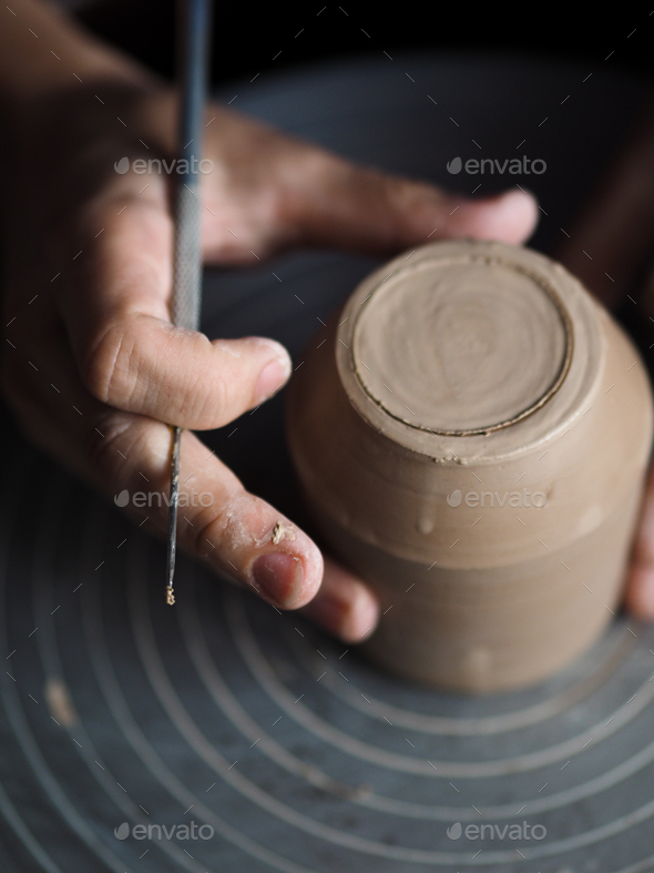 Ceramist young woman making clay product on pottery lathe in her studio, workshop, front view.