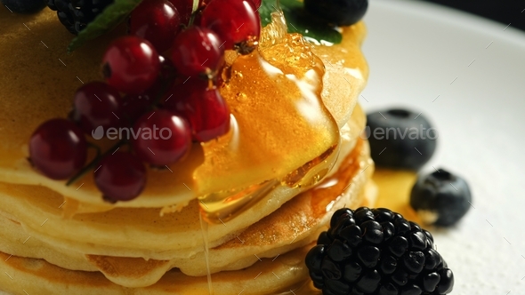 homemade pancakes or crepes decorated on top with forest berries - red currant, blackberry blueberry