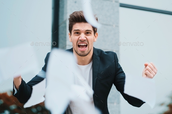 furious male office worker throwing crumpled paper,having nervous breakdown at work, screaming anger
