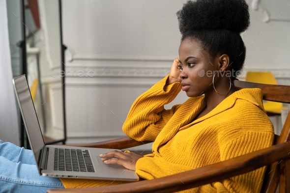 Thoughtful serious Black biracial woman working online on laptop, watching education videos course
