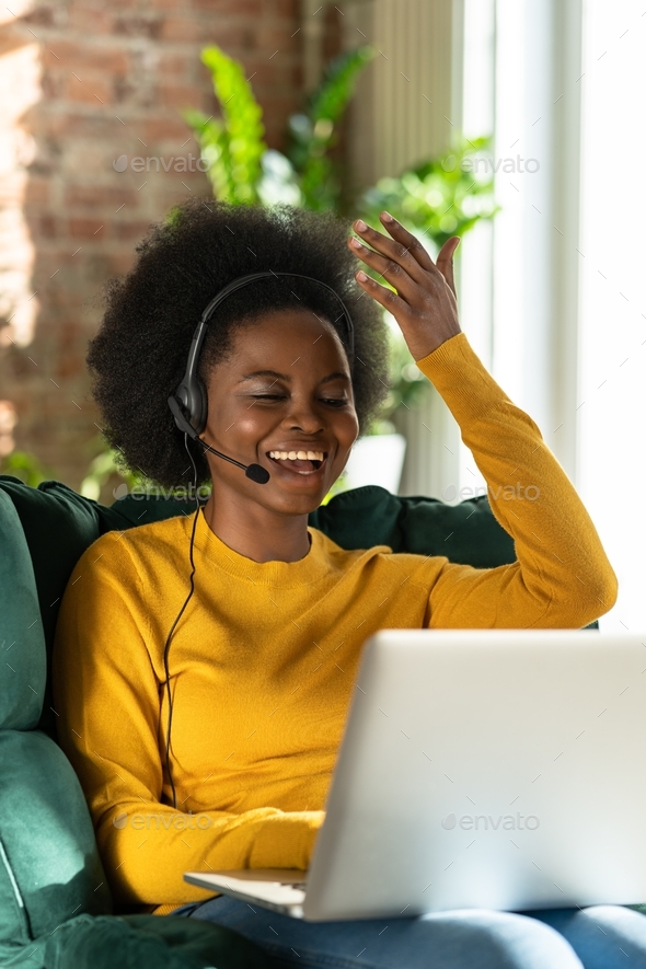 Funny black woman wear headphones while talking to client in video chat, teach online. Call support